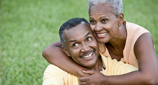 Man and woman sitting in the grass hugging 
