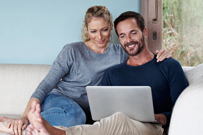Happy husband and wife checking their MyPlans account on a laptop