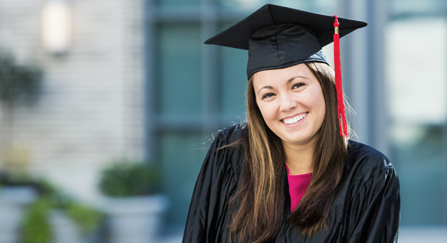 smiling female college graduate wearing graduation cap and gown 